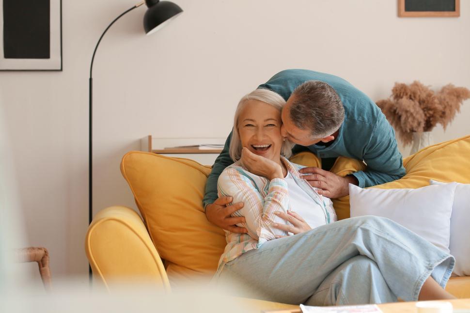 Free Image of Joyful couple laughing together on a cozy yellow couch 