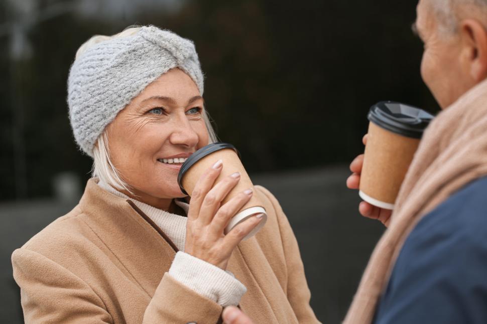 Free Image of Happy couple enjoying hot drinks in winter clothes 