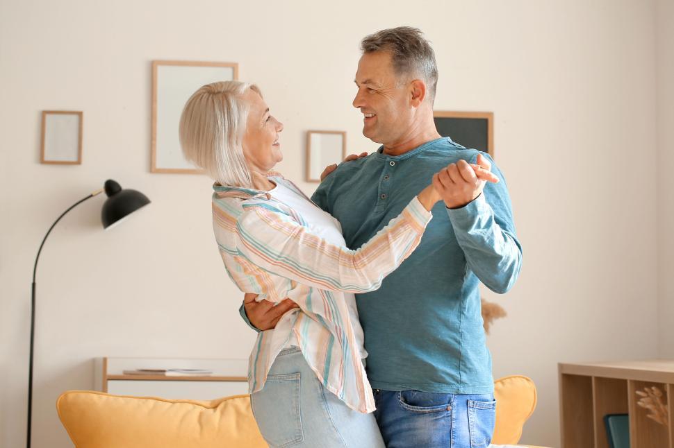 Free Image of Elderly couple dancing indoors, smiling in each other s arms 