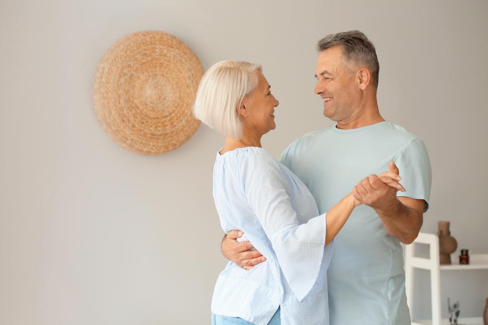 Free Image of Elderly couple dancing joyfully in bright, cozy home 