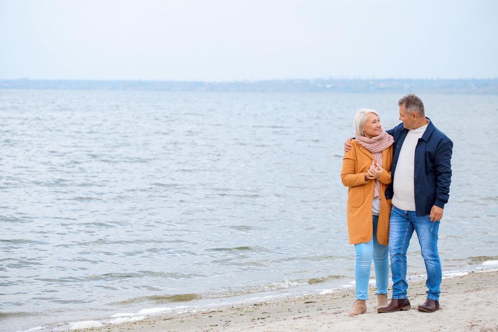 Free Image of Couple walking by the sea on a cool day. 