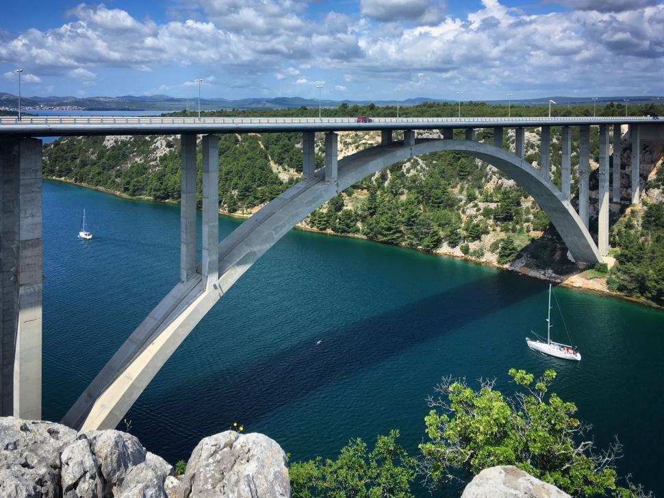 Free Image of Modern concrete bridge spanning blue river below 