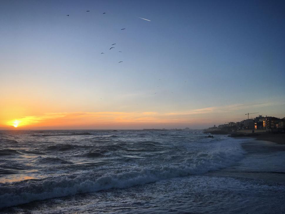 Free Image of Sunset over a wavy ocean with a clear sky horizon 