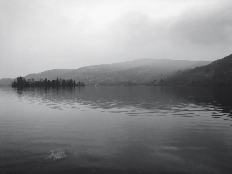 Free Image of Misty black and white lake landscape with distant hills 
