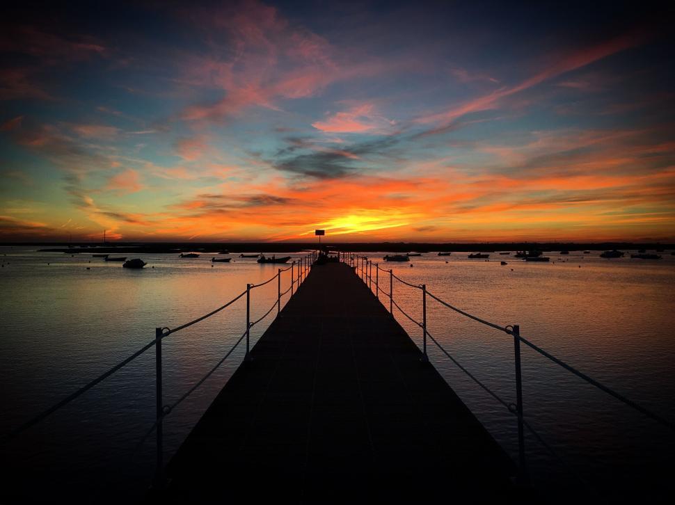 Free Image of Sunset at the pier leading into a calm ocean 