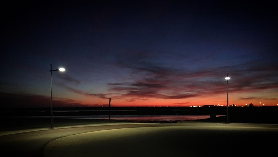 Free Image of Street lamps illuminating path under vibrant sunset sky. 