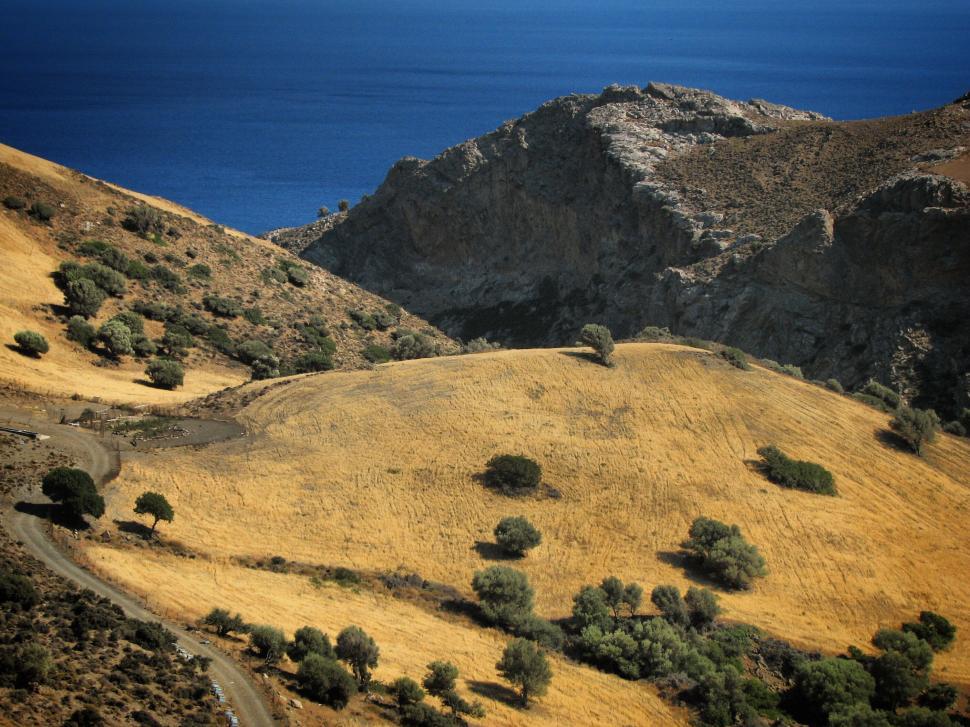 Free Image of Arid landscape with rolling hills leading to the sea. 