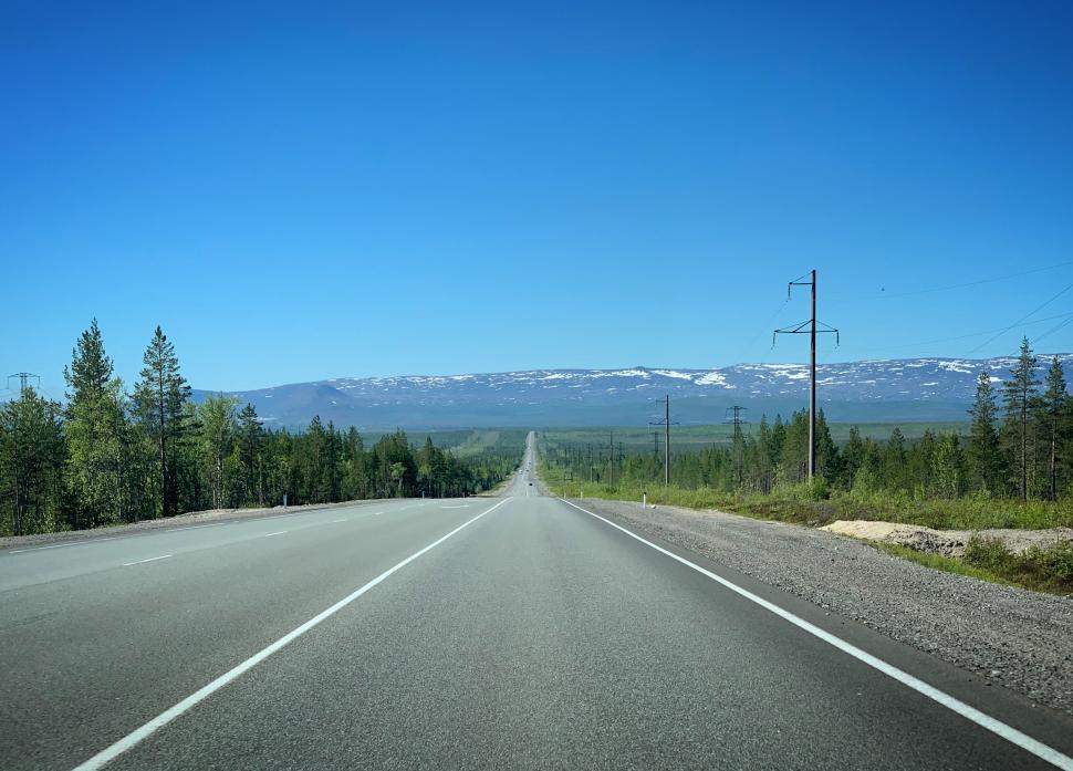Free Image of Endless open road stretching through lush green forests. 