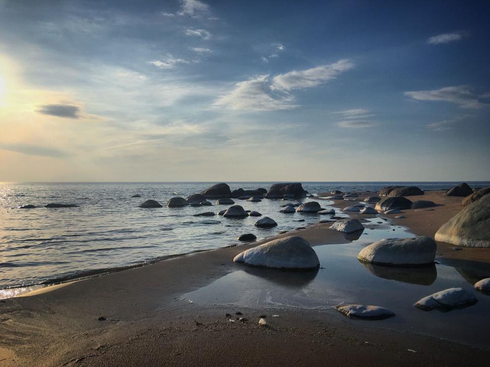 Free Image of Peaceful beach with scattered rocks at sunrise. 