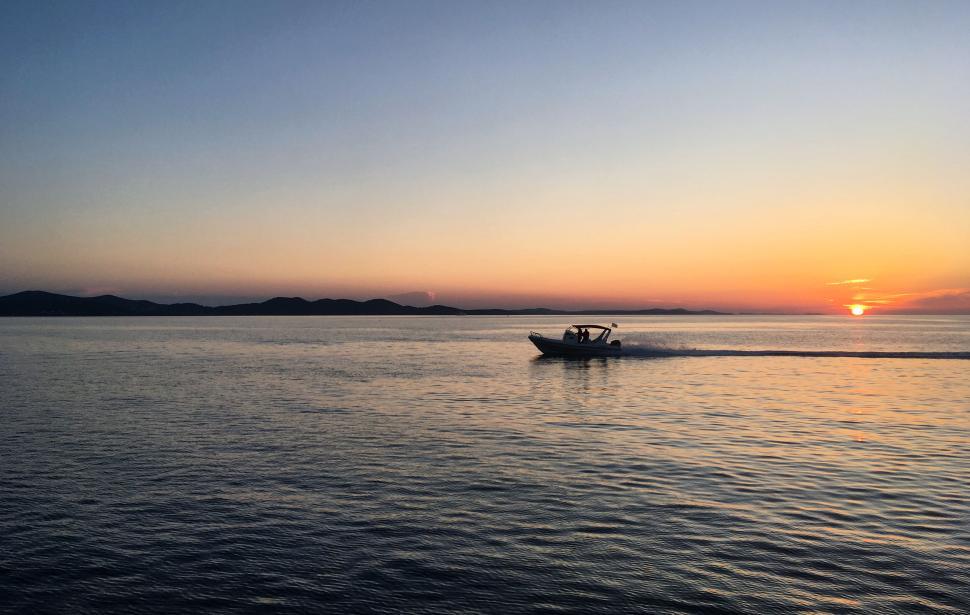 Free Image of Boat speeding on calm water at sunset, tranquil scene. 