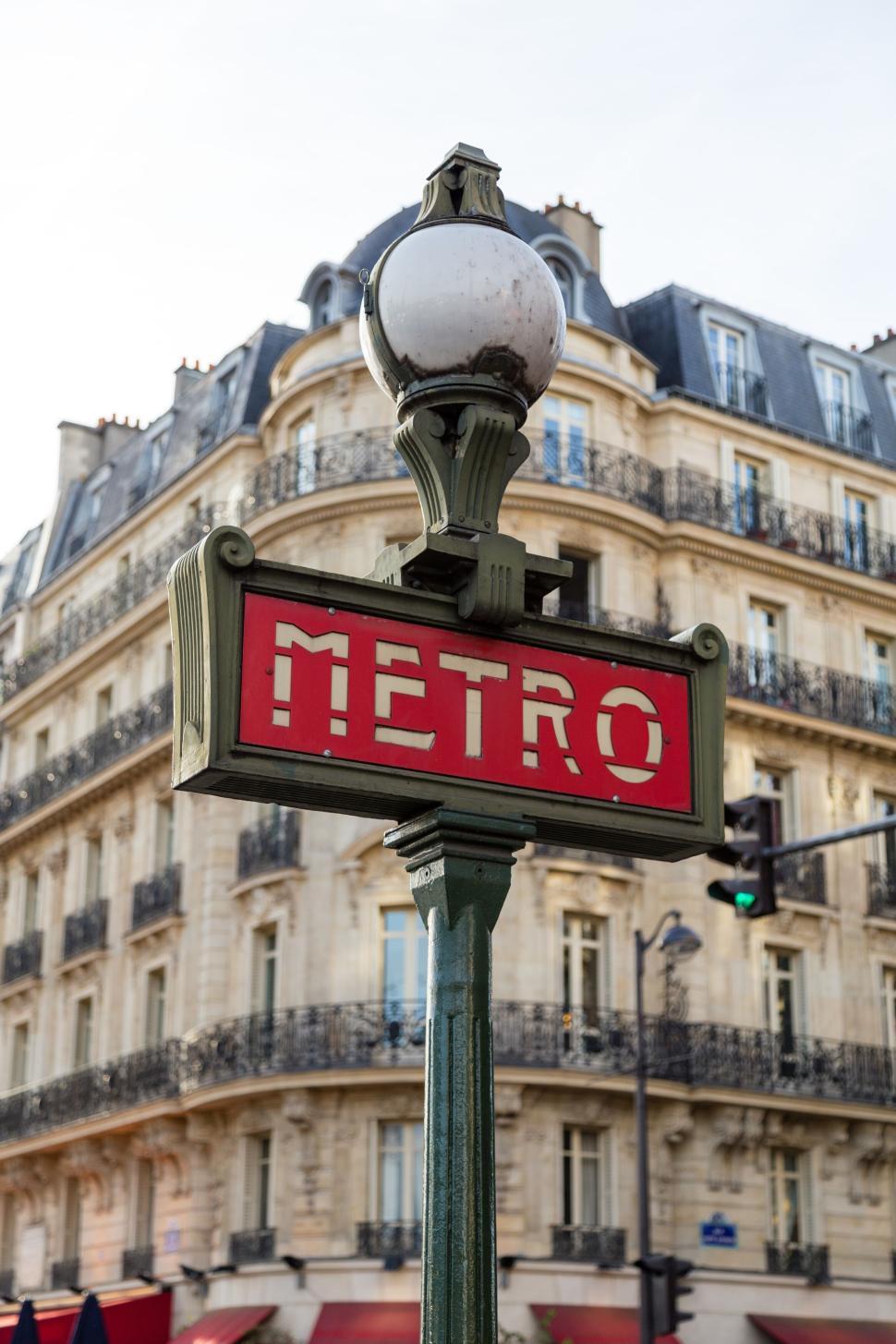 Free Image of Vintage metro sign with Parisian building backdrop. 