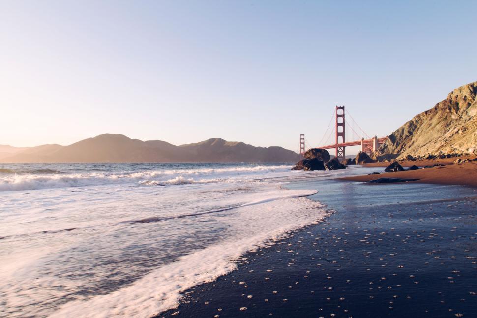 Free Image of Golden Gate Bridge with waves crashing on the shore. 