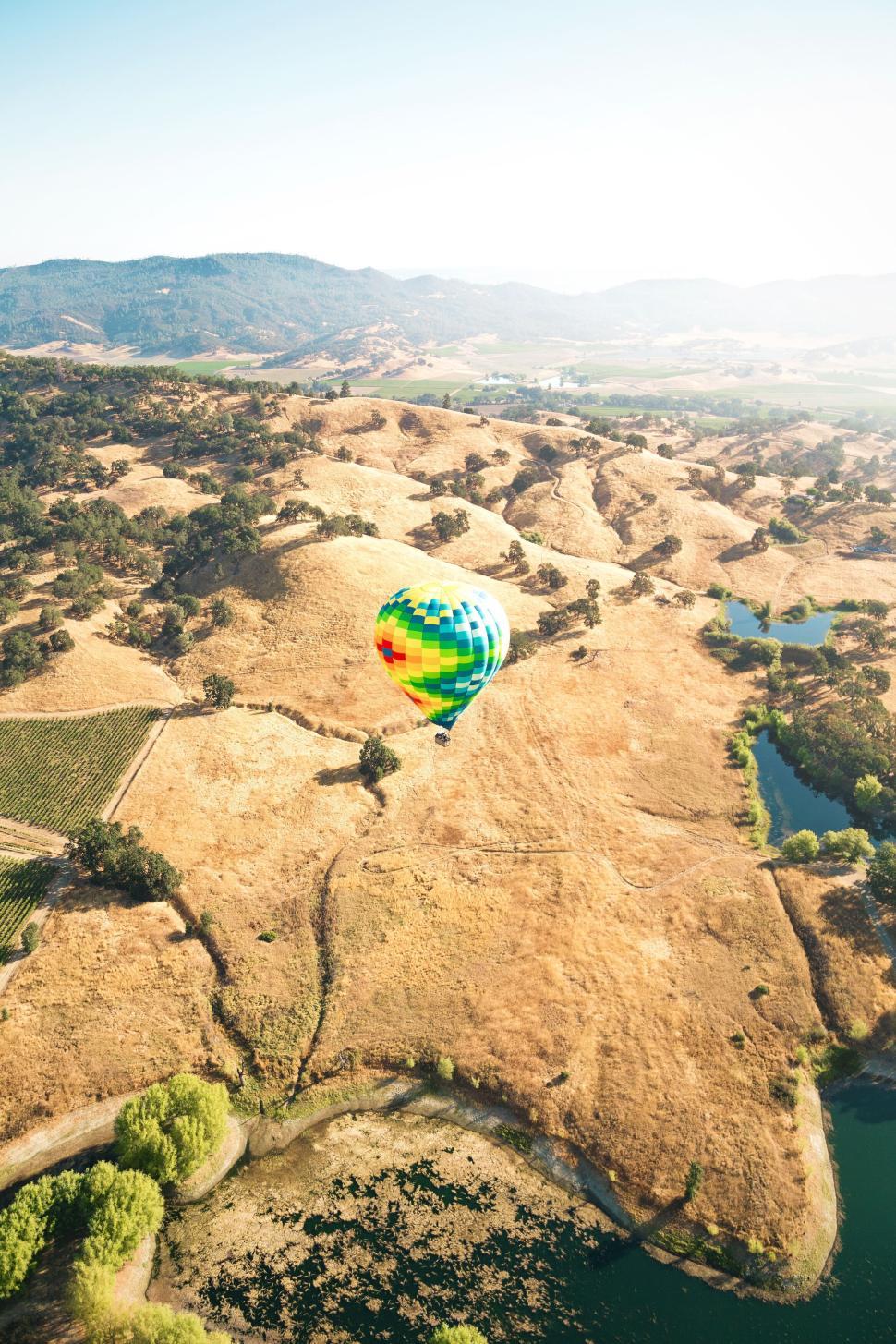 Free Image of Vibrant hot air balloon over rolling hills. 