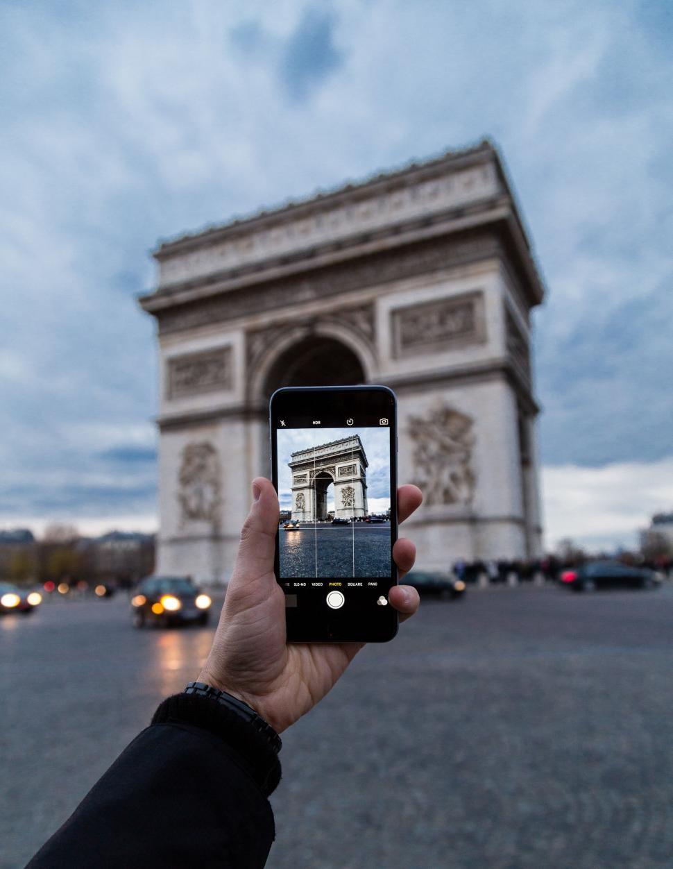 Free Image of Phone captures Arc de Triomphe at dusk with city lights. 