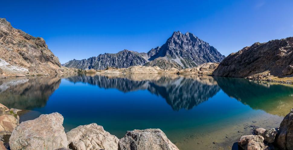 Free Image of Crystal clear lake reflecting rugged mountain scenery 