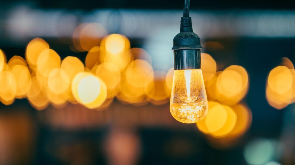 Free Image of Hanging vintage-style light bulb glowing warmly. 
