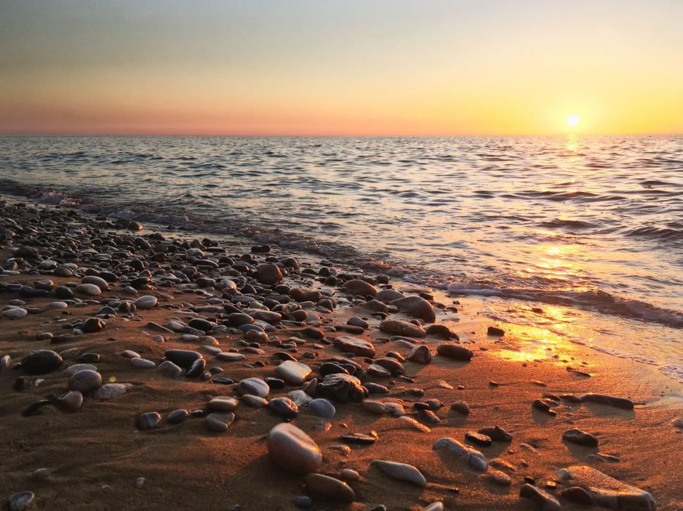 Free Image of Rocky beach at sunrise with colorful sky and waves 