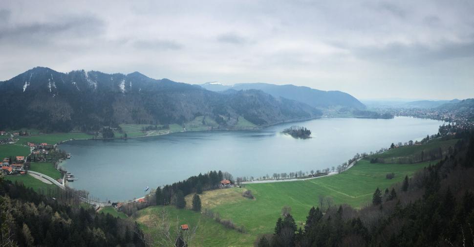 Free Image of Panoramic view of a lake surrounded by green hills 