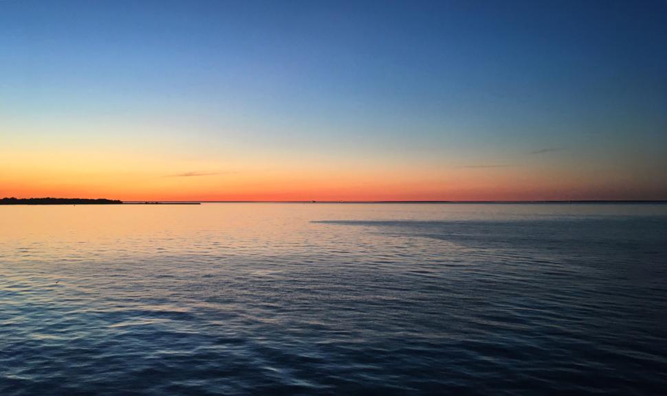 Free Image of Calm water at sunset with blue and orange hues blending 