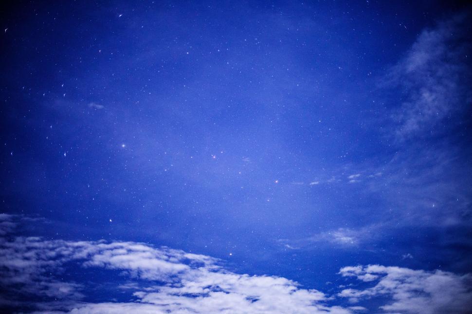Free Image of Night sky with plethora of stars and some clouds below 