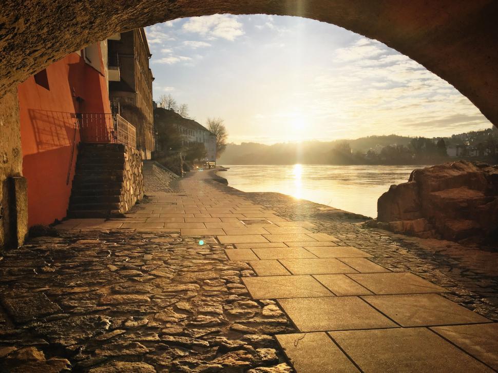Free Image of Path under archway near river during sunset 