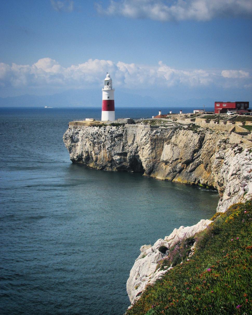Free Image of White and red lighthouse on a cliff by the sea 