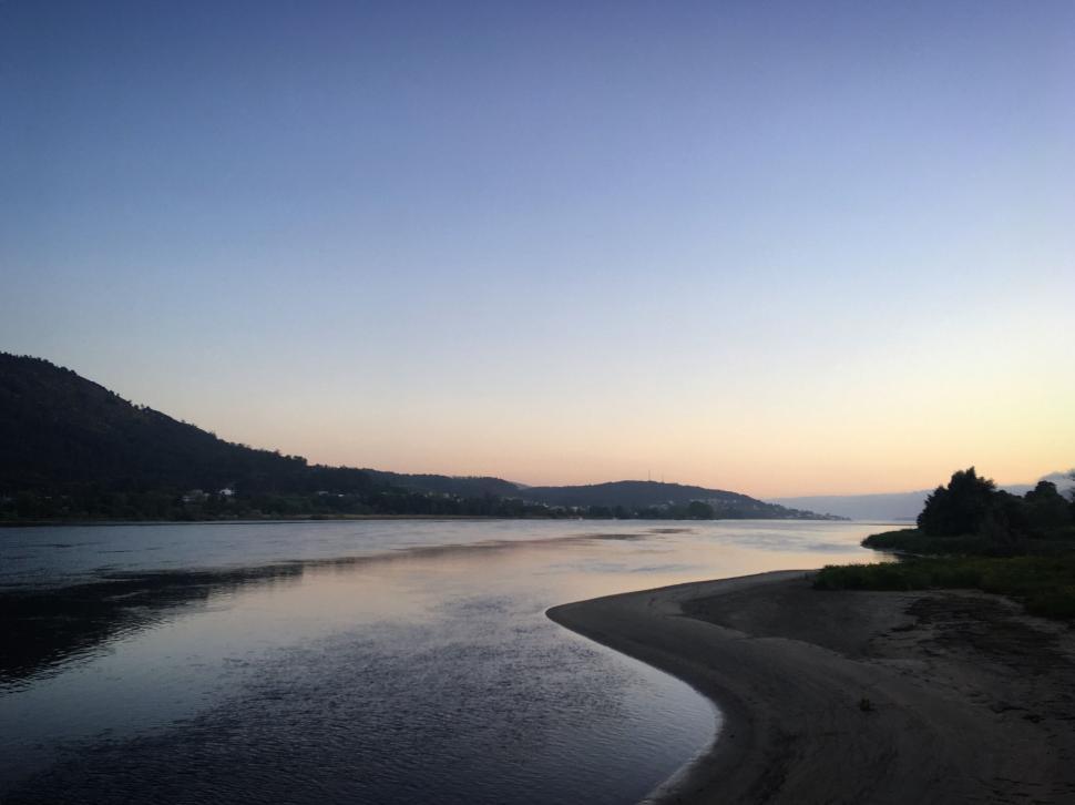Free Image of Calm river at dusk with a gentle gradient in the sky. 