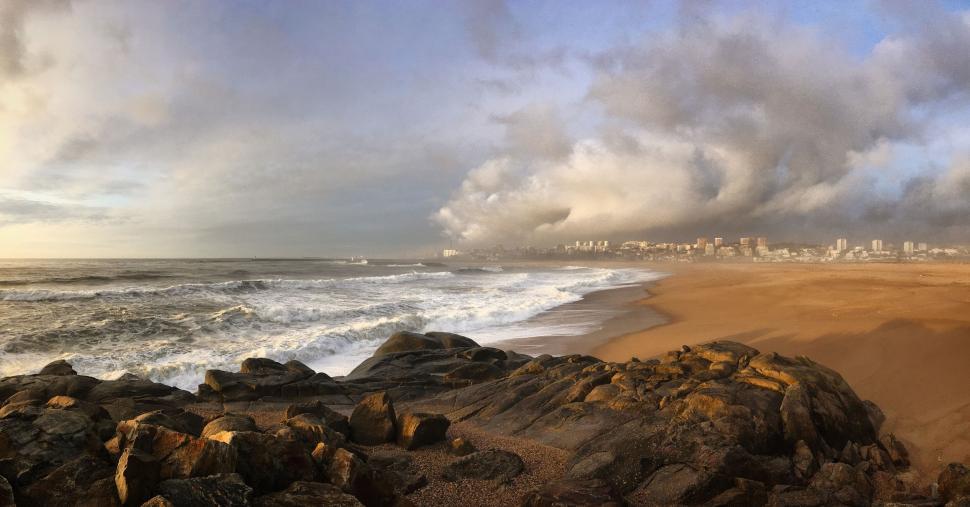 Free Image of Vast sandy beach with rocks and cloudy sky 