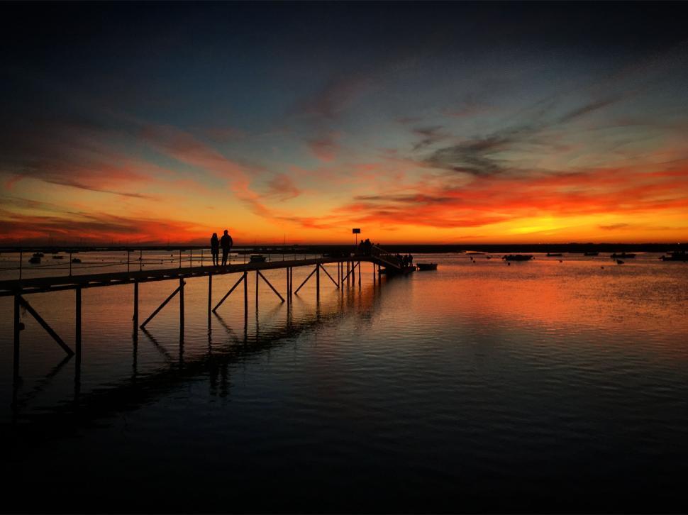 Free Image of Silhouetted people on pier at beautiful sunset sky 