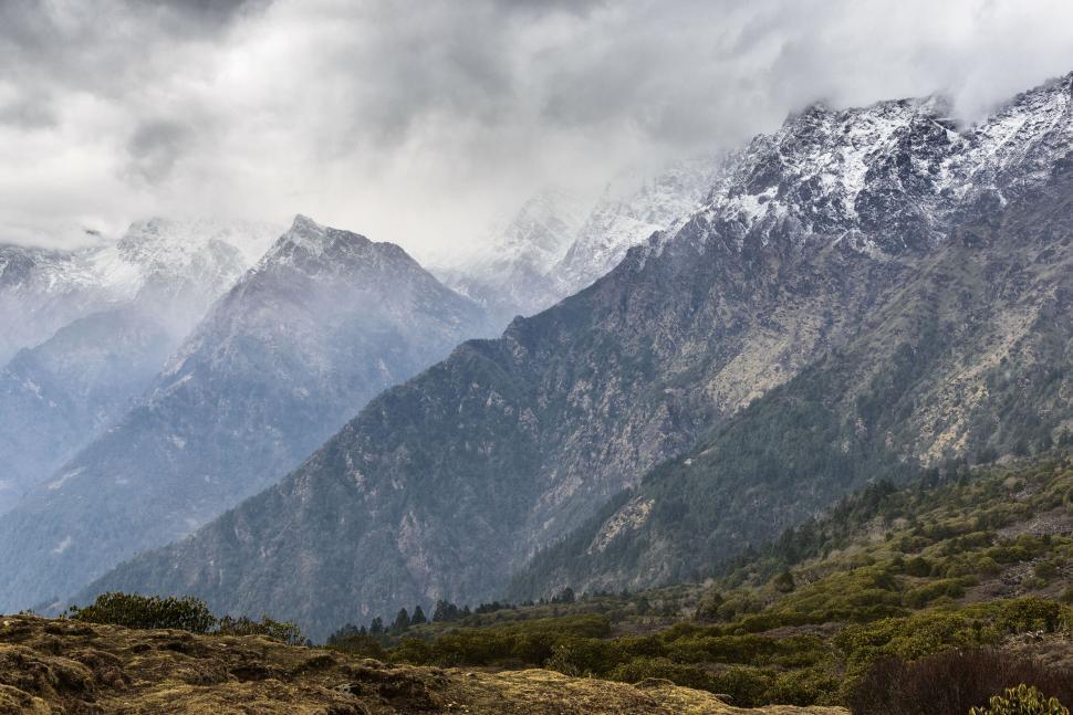 Free Image of Snow-capped rugged mountains under a cloudy sky. 