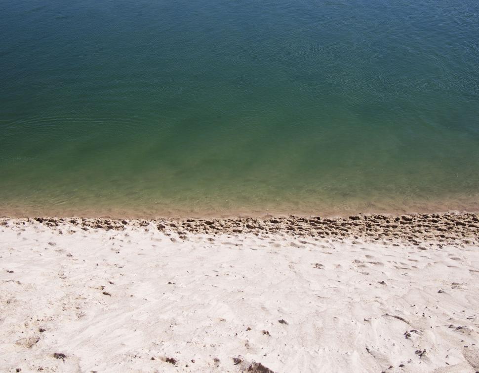 Free Image of Calm shoreline with clear water meeting sandy beach. 
