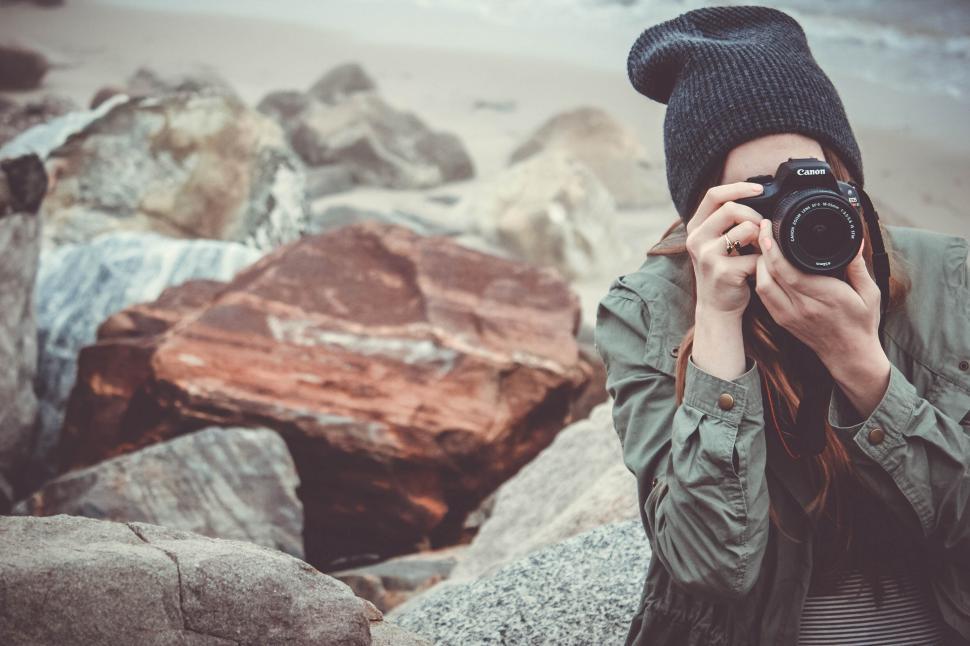 Free Image of Person in beanie photographing scenic view from rocky shore. 