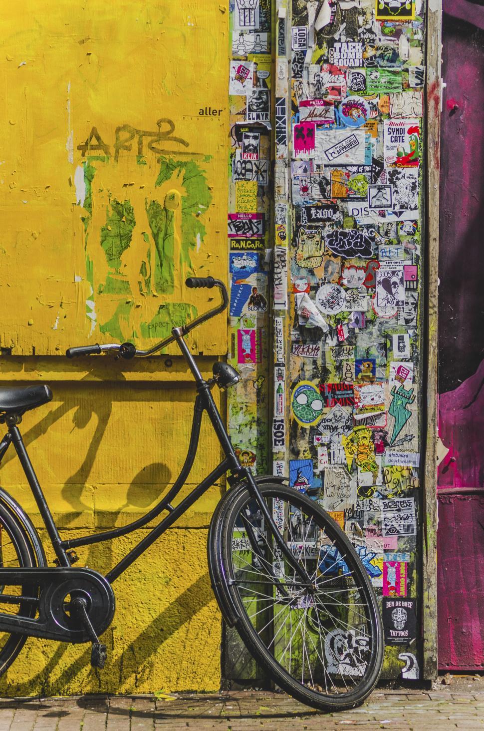 Free Image of Bicycle leaning against vibrant wall covered with graffiti. 
