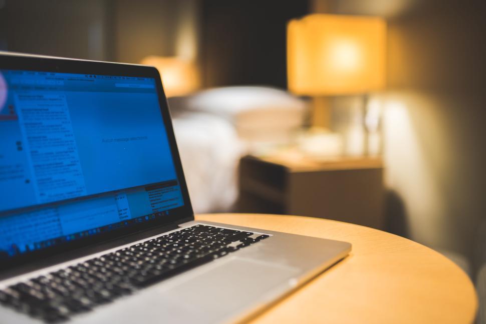 Free Image of Laptop on a wooden table in a cozy well-lit room. 