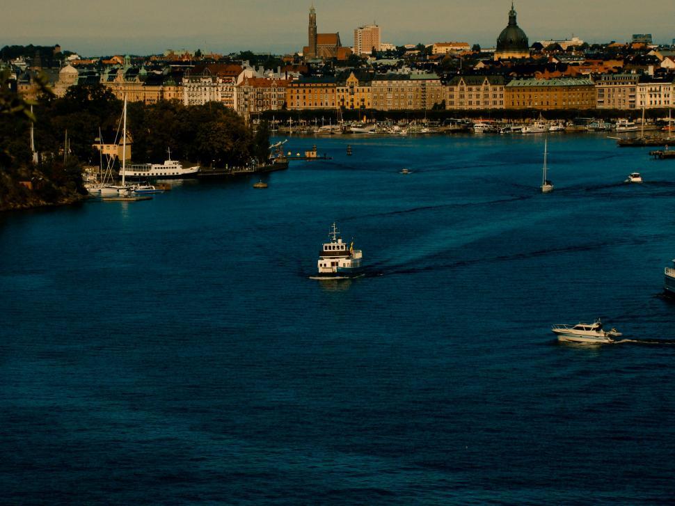 Free Image of Waterway with boats leading to a distant city skyline. 