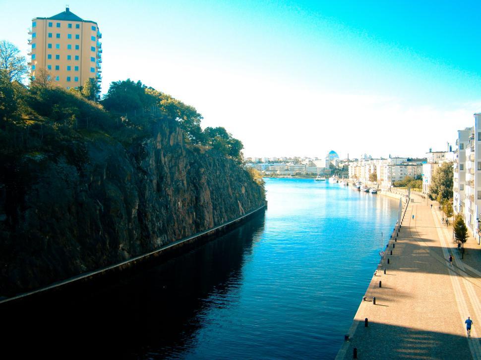 Free Image of Urban canal flowing under blue sky with buildings around 