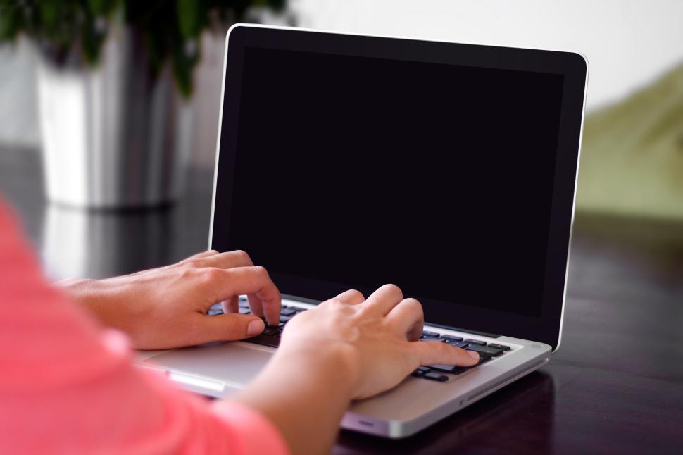 Free Image of Hands typing on laptop with blank screen on wooden table 
