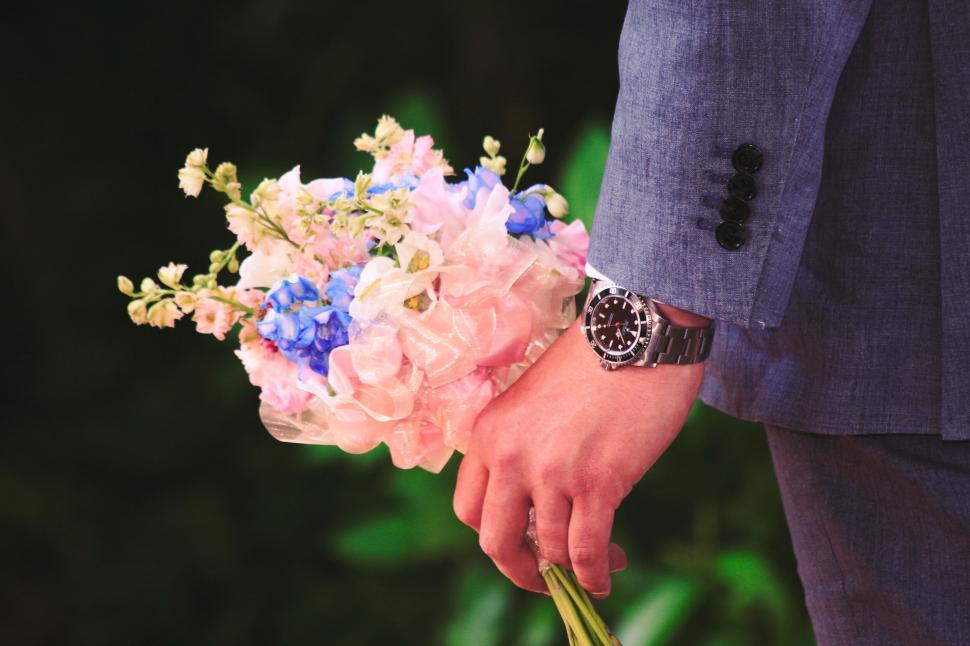 Free Image of Person in suit holding a bouquet of colorful flowers. 