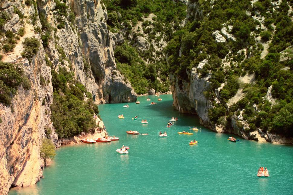 Free Image of Boats on emerald waters between rocky cliffs and greenery. 