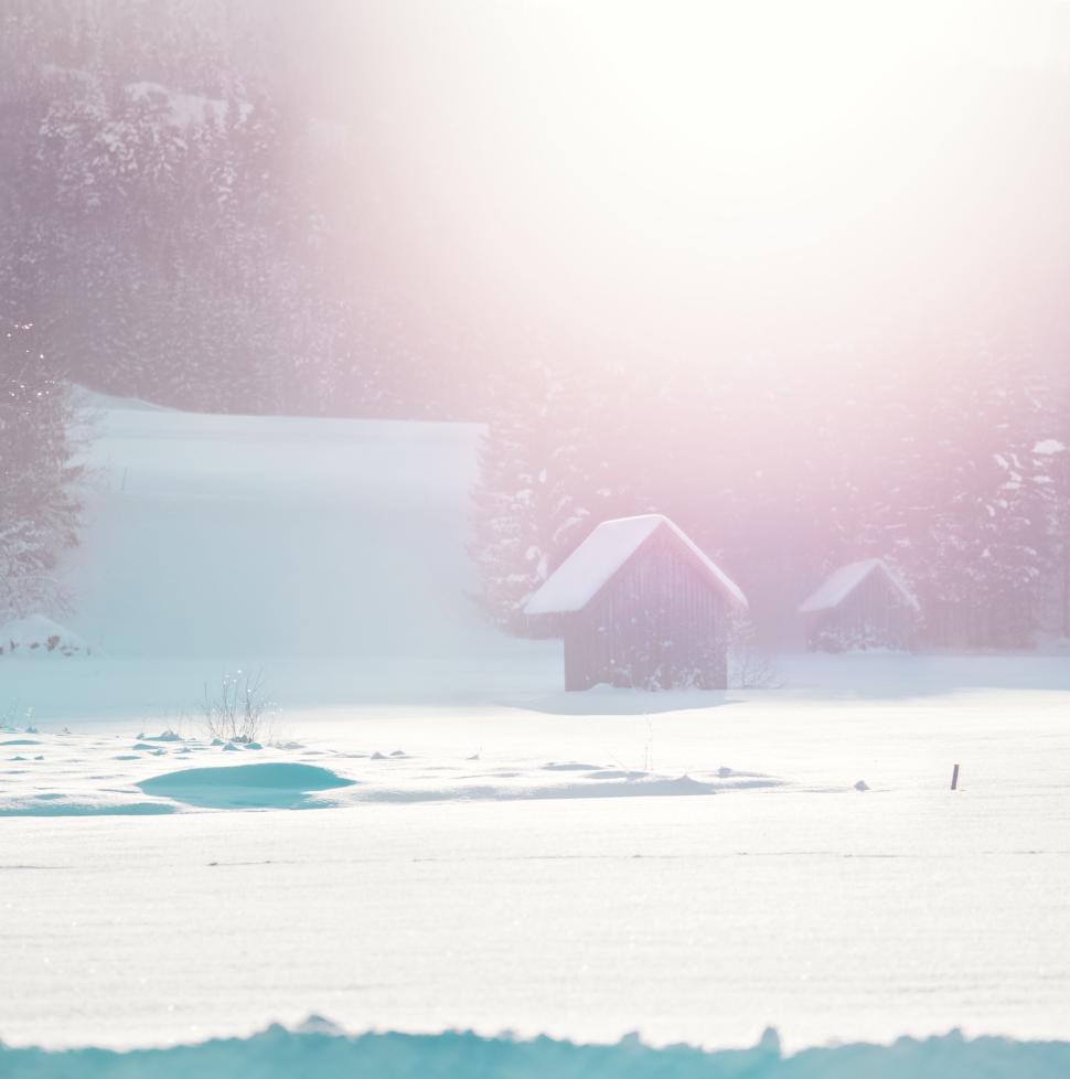 Free Image of Cabin in snowy landscape under bright sunlight glow 