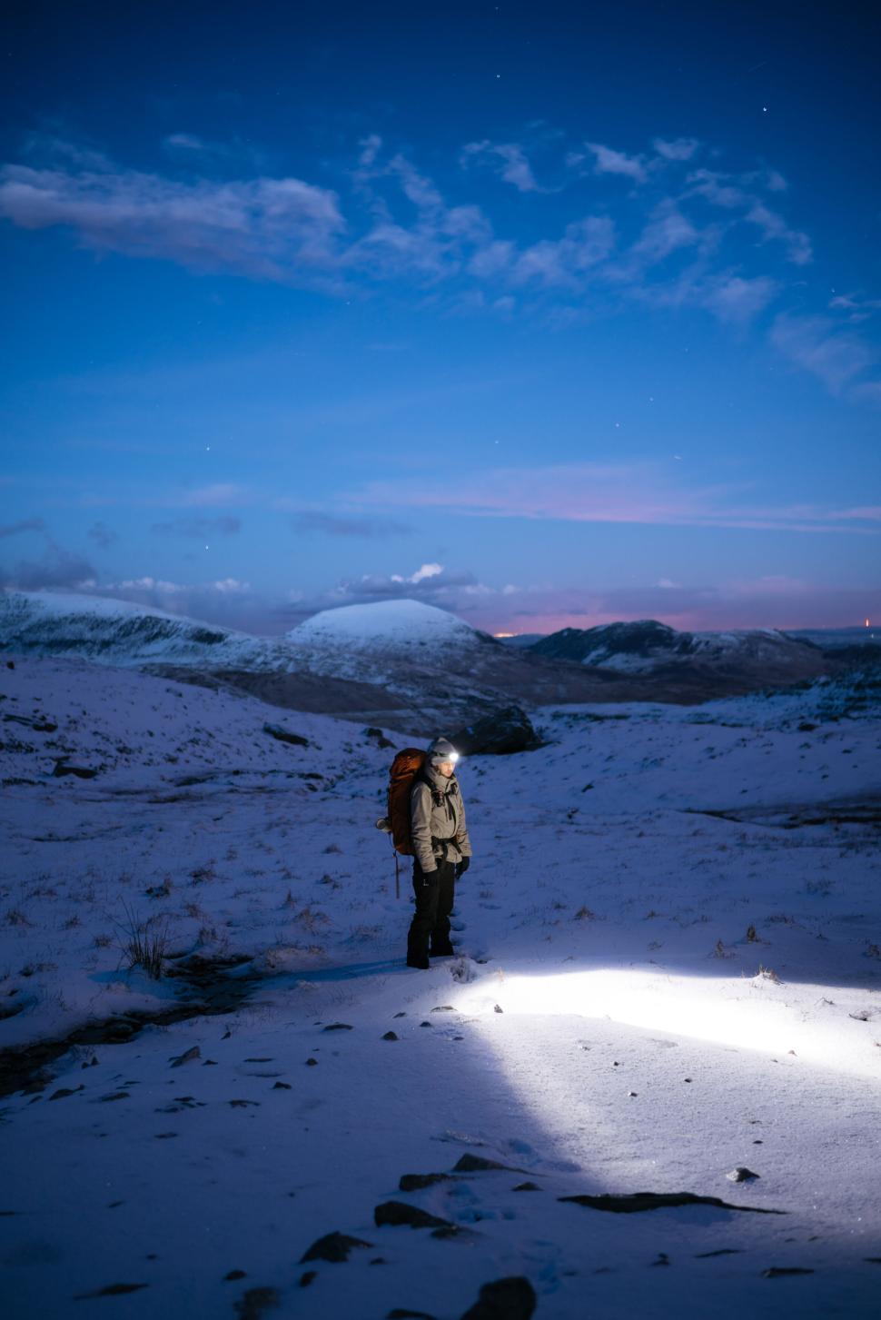 Free Image of Person standing in the snowy terrain under a twilight sky. 