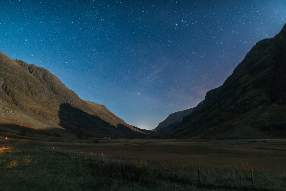 Free Image of Night sky over mountainous valley with stars twinkling. 