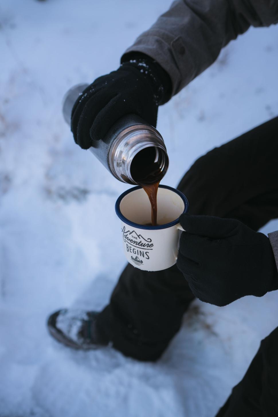 Free Image of Pouring hot coffee into mug outdoors in snowy setting. 