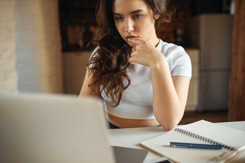 Free Image of Serious student girl participating in video group chat, learning online from home. Attractive young female freelancer working distantly using wifi on laptop. Technology, job and occupation concept 