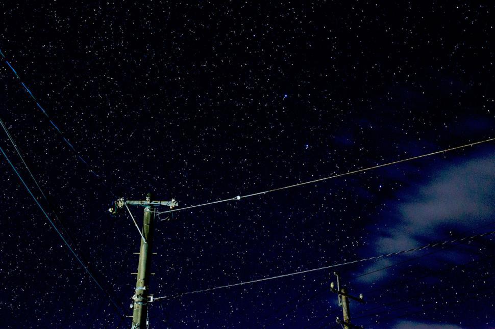 Free Image of Star-filled night sky with utility poles and cables visible 