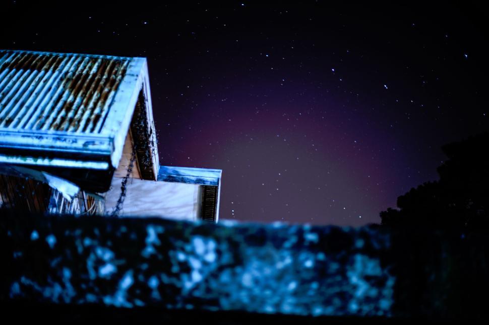 Free Image of Starry night over a rustic building with colorful lighting 