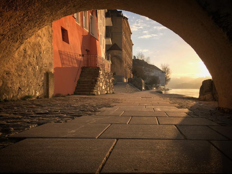Free Image of Scenic archway view leading to a riverside town at sunset 