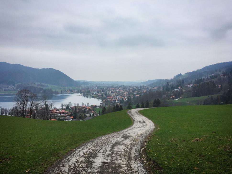 Free Image of Path through green hills overlooking lake and village 
