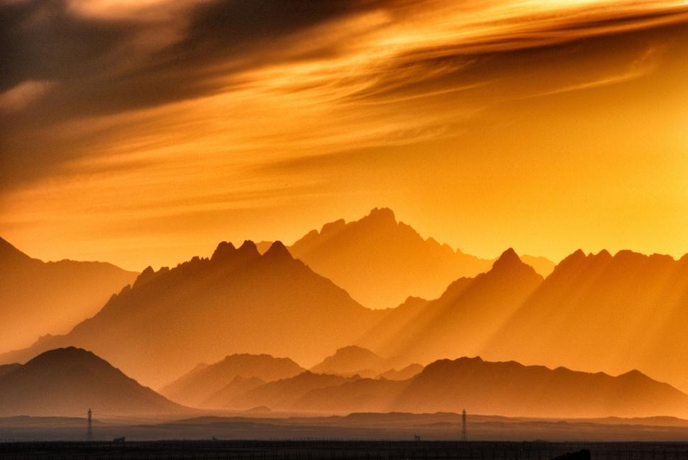 Free Image of Golden sunrise over layered mountain silhouettes 