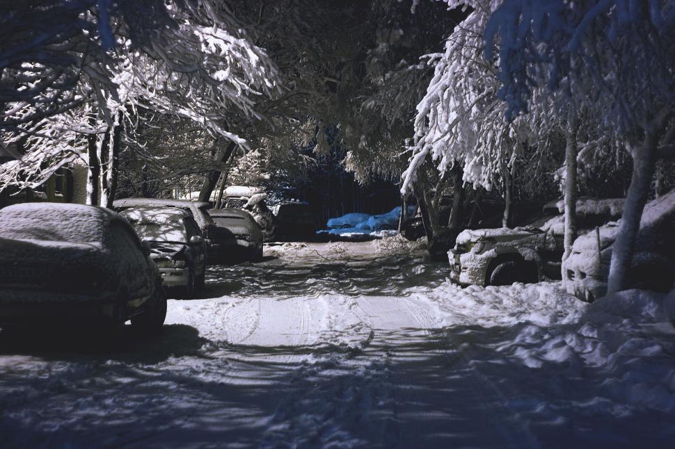 Free Image of Snow-covered cars in dark street illuminated by light. 